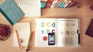 Geordneter Schreibtisch mit Büchern, Heften, Smartphone, Schreibmaterialien und einer Tastatur.