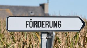 Wegweiserschild mit der Aufschrift „Förderung“ vor einem Feld.
