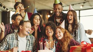 Freundesgruppe feiert gemeinsam einen Geburtstag an einem Tisch mit Kuchen und Geschenken.