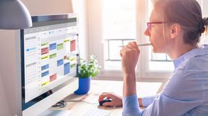 Mitarbeiterin betrachtet einen digitalen Terminkalender auf ihrem Computerbildschirm.