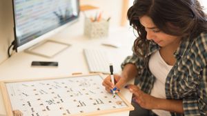 Frau trägt Termine in einen großen Kalender auf ihrem Schreibtisch ein.