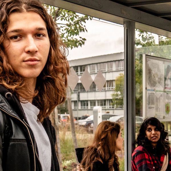 Vier Studierende warten auf dem Campus der BTU an einer Bushaltestelle auf ihre Verbindung.