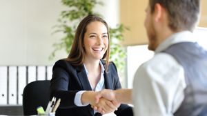 Bewerberin und Gesprächspartner begrüßen sich bei einem Vorstellungsgespräch mit einem Händedruck.