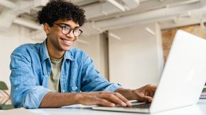 Lächelnder Student arbeitet an einem Laptop.