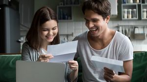 Zwei junge Erwachsene sitzen vor einem Laptop und lesen gemeinsam Briefe.