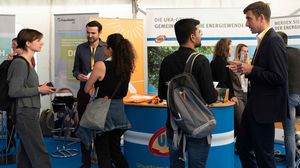 Besucherinnen und Besucher führen Gespräche an den Ständen einer Jobmesse.